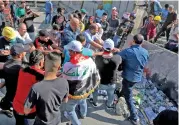  ?? (AFP) ?? Protesters pull down concrete barriers erected by security forces at Baghdad’s Khallani square on Saturday