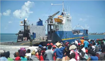  ?? — AFP ?? People wait to board a cargo ship for evacuation to Nassau at the port after Hurricane Dorian in Marsh Harbour, Great Abaco.