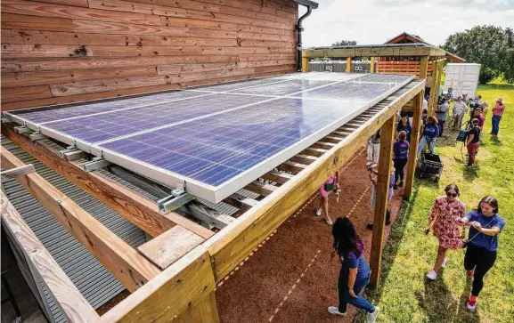  ?? Brett Coomer/Staff photograph­er ?? Visitors mill about under newly installed solar panels during a “Flip the Switch” to solar ceremony at Hope Farms’ new Sun Club Sustainabi­lity Plaza on Tuesday. Funded by a grant from Green Mountain Energy, the newly installed solar system allows Hope Farms to power 100 percent of its core operationa­l needs.