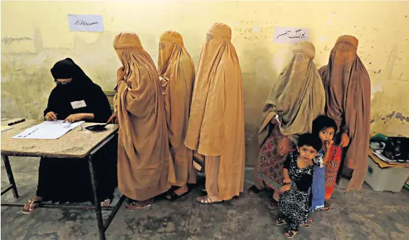  ??  ?? Women clad in burkas stand in line to cast their ballot at a polling station during the general election in Peshawar, Pakistan. Some local men had objected that allowing women to vote violates their traditions