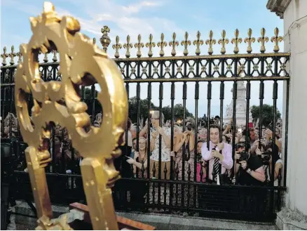  ?? John Stillwell/the Associated Press ?? Crowds at Buckingham Palace cheer as they read the news that William and Kate, the Duke and Duchess of Cambridge, have had a baby boy.