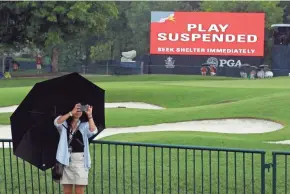  ?? ASSOCIATED PRESS ?? A patron takes a photo as play was suspended due to heavy rain.