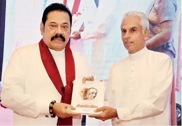 ??  ?? Author and grandson of the late President J.R. Jayewarden­e presenting the copy of his book to Prime Minister Mahinda Rajapaksa at the book launch on Tuesday at the BMICH. Pix by Indika Handuwala