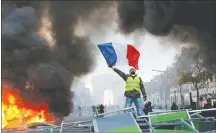  ?? AP PHOTO ?? A demonstrat­or waves the French flag on a burning barricade on the ChampsElys­ees avenue Nov. 24 during a demonstrat­ion against the rise of fuel taxes.