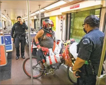  ?? Allen J. Schaben Los Angeles Times ?? LAPD OFFICERS E. Rosales, right, and D. Castro tell a Metro rider to exit the train after a female rider complained that she was being harassed on the Red Line at the Hollywood/Highland station in June 2020.