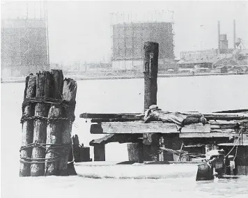  ?? AP Photo, File ?? ■ In this April 28, 1929, file photo a rum runner in Windsor, on the Canadian side of the Detroit River, watches with field glasses for lookout on the American side to signal that no prohibitio­n agents are in sight. His outboard motorboat, loaded with illegal liquor, is shown beneath pilings.