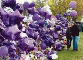  ?? Mark Ralston / AFP / Getty Images ?? Prince fans look to contribute to a sea of balloons and flowers at a memorial wall outside the music legend’s Paisley Park compound Sunday in Chanhassen, Minn.