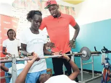  ??  ?? Usain Bolt looks on while Anna-Lee Evans assists Peta-Gaye McKenzie to do bench presses at the Edwin Allen High School in Frankfield Clarendon for the official opening of the new gym for the winners of the Digicel Grand Prix.