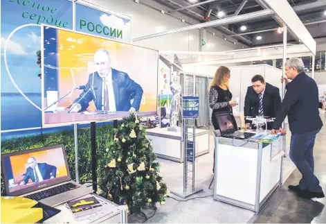  ??  ?? — AFP photo Participan­ts of ECOTECH forum gather next to a screen broadcasti­ng Russian President Vladimir Putin’s annual press conference in Moscow on Dec 14.