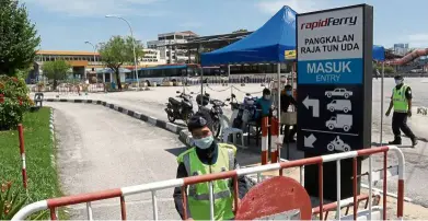  ??  ?? Temporary setback: An auxiliary police officer closing the entrance to the Raja Tun Uda ferry terminal in George Town after the ferry service was disrupted.