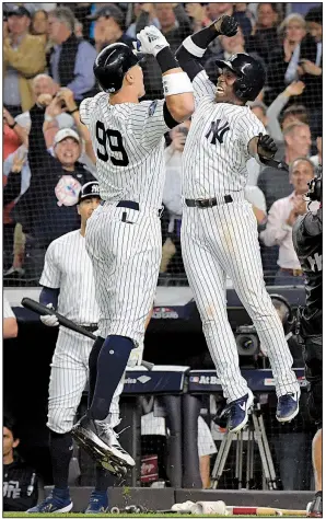  ??  ?? AP/BILL KOSTROUNAa­ron Judge (99) and Andrew McCutchen of the New York Yankees celebrate after Judge’s two-run home run in the first inning during the Yankees’ victory over the Oakland Athletics in the American League wild-card game Wednesday night at Yankee Stadium in New York.