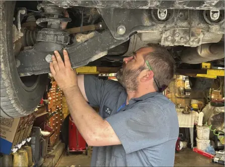  ?? TOM KRISHER — THE ASSOCIATED PRESS ?? Mechanic Jon Guthrie inspects the underside of a 2014Honda Ridgeline pickup truck at Japanese Auto Profession­al Service in Ann Arbor, Michigan. People are keeping their vehicles longer due to shortages of new ones and high prices. That drove the average U.S. vehicle age up to a record 12.5years in 2022, according to S&P Global Mobility.