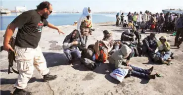  ??  ?? Some illegal migrants with a Libyan security officer Photo: NET