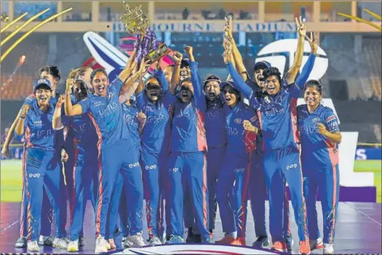  ?? AFP ?? Mumbai Indians players with the trophy after winning the Women's Premier League final against Delhi Capitals at the Brabourne Stadium on Sunday.