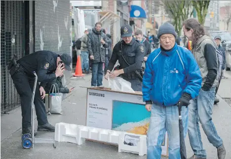  ?? JASON PAYNE ?? Vancouver police officers try to ascertain whether or not a TV is stolen on E. Hastings Street in the Downtown Eastside on Saturday. Some drug users say an increased police presence in the area recently could prevent people from using supervised...