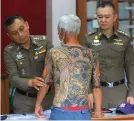  ??  ?? Japanese gang member Shigeharu Shirai displays his tattoos to police