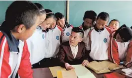  ??  ?? Volunteer teacher Zhang Qingqun discusses classwork with his students at the Shanghai Experiment­al School in Shigatse.