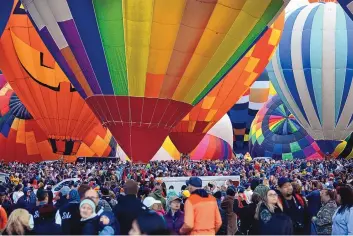  ?? JIM THOMPSON/JOURNAL ?? Crowds await a mass ascension launch during the 2018 Albuquerqu­e Internatio­nal Balloon Fiesta. The annual event at Balloon Fiesta Park is typically Albuquerqu­e’s largest tourist attraction, but COVID-19 concerns led organizers to shut it down in 2020. The Balloon Fiesta is set to resume in October.