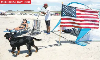  ?? Kin Man Hui / San Antonio Express-News ?? Duane Bailey of San Antonio resets a fishing line as girlfriend Susan Heckaman of Austin soaks in the sun on a beach in Port Aransas. Bailey, a Marine veteran, said he made the trip to fish and to support the local economy recover from Harvey.