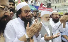  ?? —AP ?? LAHORE: Hafiz Saeed (third left), the leader of Pakistan’s anti-Indian group Lashkar-e-Taiba, that was banned but resurrecte­d as the Jamaat-ud-Daawa, prays for Indian Kashmiris with others during an anti-Indian rally in Lahore.