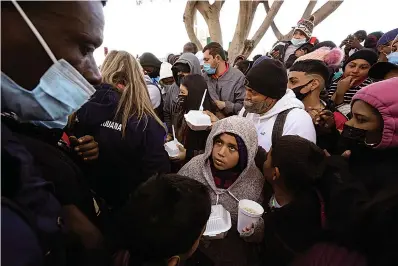  ?? Associated Press ?? ■ Asylum seekers receive food Friday as they wait for news of policy changes at the border in Tijuana, Mexico. After waiting months and sometimes years in Mexico, people seeking asylum in the United States are being allowed into the country starting Friday as they wait for courts to decide on their cases, unwinding one of the Trump administra­tion's signature immigratio­n policies that President Joe Biden vowed to end.