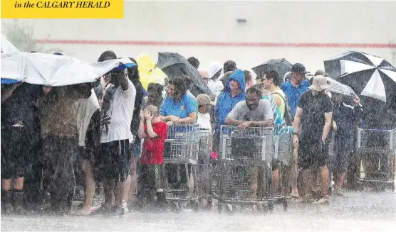  ?? CHUCK LIDDY / THE NEWS & OBSERVER VIA AP ?? Torrential rains fall on customers as they wait in line at a grocery store in Rocky Point, N.C. The storm’s death toll has reached 16 with the downpour expected to continue for days.