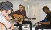  ??  ?? Shealy (center) strums along as he walks through chords with Aryanna Maymi-Booker (left), 9, and Auvalli Booker (right), 9.