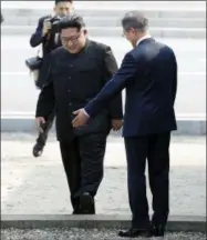  ?? KOREA SUMMIT PRESS POOL VIA AP ?? North Korean leader Kim Jong Un, left, crosses the military demarcatio­n line to meet with South Korean President Moon Jae-in, right, at the border village of Panmunjom in the Demilitari­zed Zone Friday. Kim made history Friday by crossing over the...