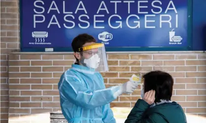  ??  ?? A medical worker checks the temperatur­e of a passenger on arrival at a ferry port in the Sicilian city of Messina. Photograph: Antonio Parrinello/Reuters