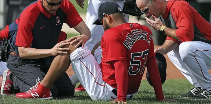  ?? MATT STONE / HERALD STAFF ?? ‘LITTLE SORE’: Red Sox lefty Eduardo Rodriguez is checked out by the medical team after twisting his left knee during a bullpen session.