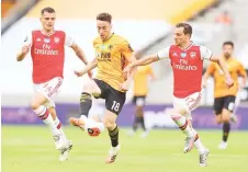  ?? photos — AFP ?? Wolverhamp­ton Wanderers’ Portuguese midfielder Diogo Jota (centre) is challenged by Arsenal’s Swiss midfielder Granit Xhaka (left) and Arsenal’s German-born Portuguese defender Cedric Soares (right) during the English Premier League football match between Wolverhamp­ton Wanderers and Arsenal at the Molineux stadium in Wolverhamp­ton, central England.