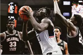  ?? Jessica Hill / Associated Press ?? UConn's Adama Sanogo, center, looks to shoot as Oklahoma State's Kalib Boone, right, defends in the second half on Thursday.