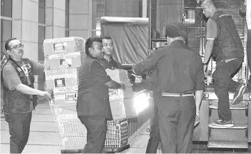  ??  ?? Police with boxes of some of the items confiscate­d on Friday from a luxury condominiu­m linked to Najib.