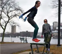  ?? Herald staFF FIle ?? MORE PARKOUR: Daisy Chen is seen working out as her mother counts repetition­s along the Charles River on March 20. Chen’s gym, Equinox, has been closed during the coronaviru­s epidemic. It’s expected that gyms in Massachuse­tts won’t be able to reopen until about the end of June.