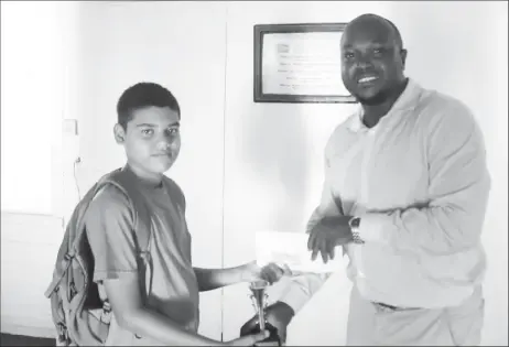  ??  ?? President of the Guyana Chess Federation James Bond (right) presents a trophy and cheque to Ghansham Alijohn, the second place winner of the junior category of the Rapid Chess Tournament that was held three weeks ago at the YMCA. A student of St...