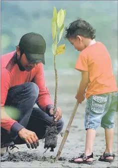  ??  ?? An Indonesian student and a boy plant a mangrove at Ujong Pancu beach in Aceh Besar, Aceh province. The event is part of Earth Day celebratio­n themed ‘Environmen­tal and Climate Literacy’, which is marked on April 22.— AFP photo