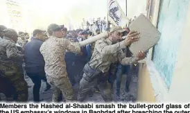  ??  ?? Members the Hashed al-Shaabi smash the bullet-proof glass of the US embassy’s windows in Baghdad after breaching the outer wall of the diplomatic mission on Tuesday.