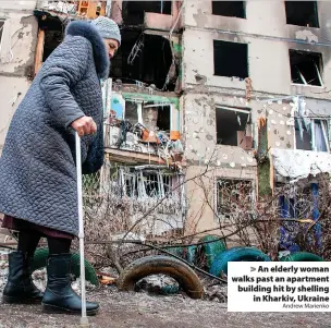  ?? Andrew Marienko ?? > An elderly woman walks past an apartment building hit by shelling in Kharkiv, Ukraine