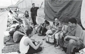  ?? Mark Mulligan / Houston Chronicle ?? Two Honduran families hoping to seek asylum in the United States wait on the Mexican side of the middle of the Brownsvill­e and Matamoros Express Internatio­nal Bridge late last month.