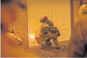  ??  ?? FEELING THE HEAT: A fireman cuts into a garage door at a burning Shadowbroo­k apartment complex in Paradise, California.