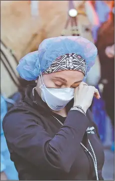  ?? (AP/Frank Franklin II) ?? A medical worker reacts April 16 as police officers and pedestrian­s cheer medical workers outside New York University Medical Center in New York. May begins where March ended, but with more hopeful news that the worst is over.