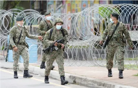  ?? AP ?? Soldiers wearing face masks patrol next to barbed wire at a newly locked down coronaviru­s affected area at old town of Petaling Jaya, Malaysia on Sunday.