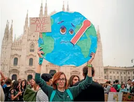  ?? AP ?? A woman in Milan, northern Italy, holds a poster of Earth during a worldwide protest – inspired by teen activist Greta Thunberg – demanding action on climate change.