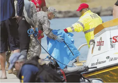  ?? AP PHOTO ?? PICKING UP PIECES: Hawaii water safety officials move debris from the downed UH-60 Black Hawk helicopter that went down offshore on Tuesday. Army, Navy and Coast Guard search teams continue the search for the crew.