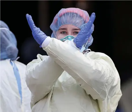  ?? MATT sToNE / HErAld sTAFF FIlE ?? BACK OFF AND STAY AWAY: A nurse at Beth Israel Deaconess Medical Center signals to stay away as they prepare to test a patient for the coronaviru­s outside the hospital on April 10. Everyone had to stay away from everyone else all year, or risk dying of the coronaviru­s, making for a miserable year.