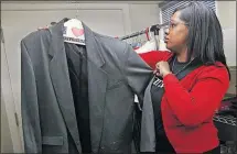  ?? [KAREN SCHIELY/AKRON BEACON JOURNAL] ?? Alicia Robinson, assistant director of the Women’s Center at Kent State University, looks at a man’s suit jacket that is one of the donated items in the Kent State Career Closet. All Kent State students will be able to put together profession­al...