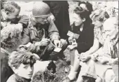  ?? U.S. Army / AFP/Getty Images ?? In this photo taken on June 6, 1944, Joseph Vaghi, center, a U.S. Navy ensign from Bethel, chats with residents of Colleville-Sur-Mer after Allied forces stormed the Normandy beaches during D-Day.