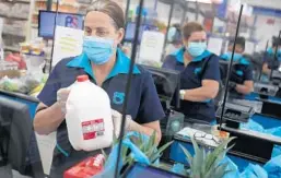  ?? JOE RAEDLE/GETTY ?? Cashiers ring up groceries amid the pandemic April 13 at a supermarke­t in Miami.