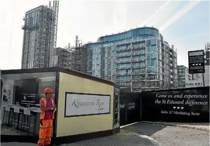  ?? PHOTO: REUTERS ?? A worker stands outside a new housing developmen­t in the upmarket London district of Kensington where 68 apartments have been assigned to rehouse families who lost their homes in the Grenfell Tower fire.