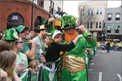  ?? The Sentinel-Record/Grace Brown ?? READY TO PADDY: Tracy Barrett hugs the “World’s Tallest Leprechaun,” Monte Everhart, on Saturday before the start of the First Ever 15th Annual World’s Shortest St. Patrick’s Day Parade.